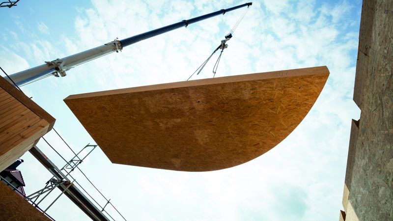 Exakt zugeschnittene Elemente werden per Kran an die richtige Position gebracht und fachmännisch montiert. Foto: Swiss Krono Tex GmbH & Co. KG / Foto: tm studios