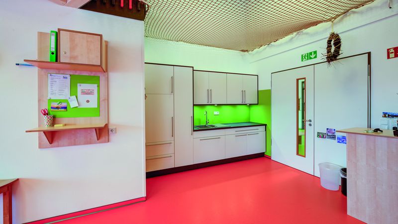 Auch in Nebenbereichen wie Fluren, Ankleidungs- und Kocharealen ist das Gestaltungskonzept von hellen Räumen mit Rot- und Grünakzenten deutlich erkennbar. Foto: Swiss Krono Tex GmbH & Co. KG / Foto: tm studios