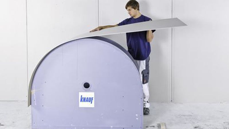 Eine Biegeschablone können Sie sich ganz einfach aus Gips- oder Holzwerkstoffplatten zuschneiden. Die vorgenässte Platte an einer Seite fixieren und langsam darüber biegen. (Bild: Knauf Gips KG)