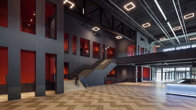 Die geradlinige Architektur des Gebäudes wird aufgelockert durch die keramischen Bodenfliesen und das wellenförmige Verlegemuster.