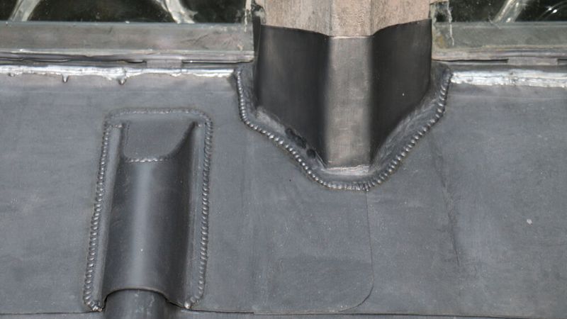 Detailaufnahme einer Bleiverkleidung auf einem Dach, die präzise Handwerkskunst zeigt.