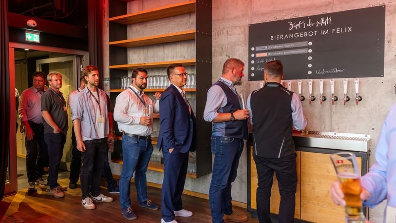 Eine Gruppe von Menschen steht in einer Bierbar in einer Schlange, um Bier zu zapfen.