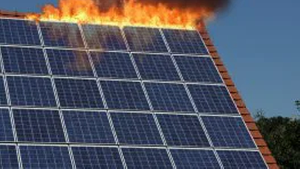 Brennende Solarmodule auf einem Schrägdach: Sichtbare Flammen und dichter schwarzer Rauch oberhalb eines Photovoltaik-Arrays, das auf einem Hausdach installiert ist. Das Bild zeigt eine akute Brandlage und mögliche Beschädigungen der Solaranlage.