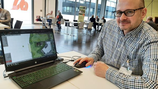 Mann mit Laptop, der ein Programm zeigt.