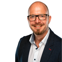 Hauptmotiv: Porträt eines lächelnden Mannes mit Brille. Der Mann trägt ein weißes Hemd und ein dunkles, gepunktetes Jackett und ist vor einem weißen Hintergrund in einer halbnahen, professionellen Business-Aufnahme zu sehen. Freundlicher, selbstbewusster Ausdruck, geeignet für Firmenporträts oder berufliche Profile.