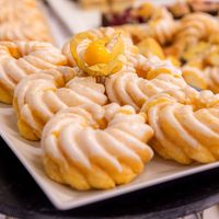 Ein Teller mit köstlichem Cremegebäck, dekoriert mit einer Physalis, im Vordergrund.