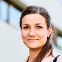 Ein Porträt einer lächelnden Frau im Freien vor einem Gebäude.