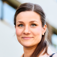 Ein Porträt einer lächelnden Frau im Freien vor einem Gebäude.