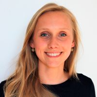 Porträt einer Frau mit langen blonden Haaren vor hellem, neutralem Hintergrund. Sie trägt ein schwarzes Oberteil und kleine Ohrringe. Das Gesicht wurde unscharf/gepixelt dargestellt. Mittlere Nahaufnahme mit natürlicher Beleuchtung und ruhiger, sachlicher Stimmung.