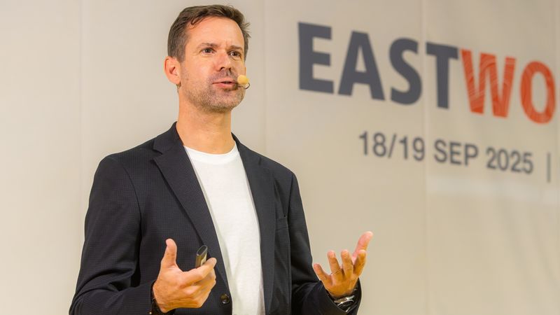 Ein Sprecher hält einen Vortrag auf einer Konferenz mit dem Titel "EASTWO" im Hintergrund.